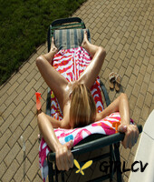 skinny girl oils up while relaxing on a lounge chair near an outdoor pool