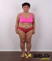 older amateur strips down to her birthday suit in front of a white wall