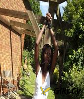 black girl is cleaved gagged and bound with her hands above her head in a yard